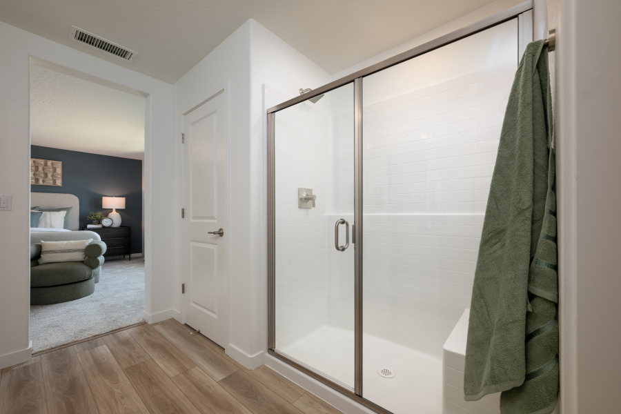 A bathroom with a shower unit and a bed.