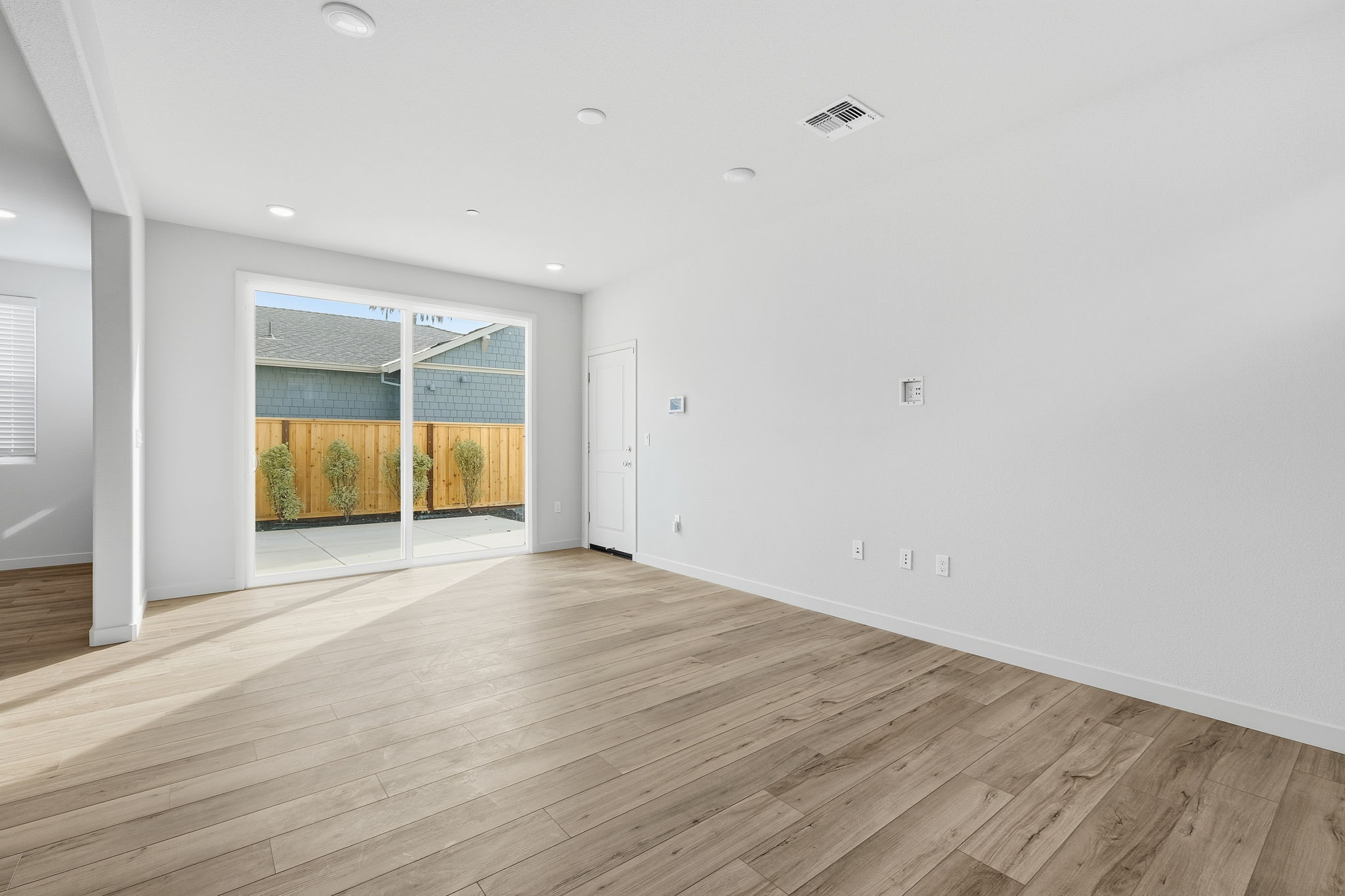 A room with a wood floor and a window with a view of the ocean.