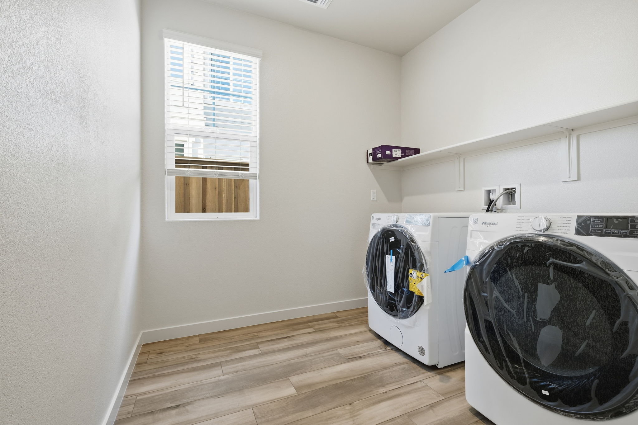 A room with a white wall and a wood floor with a white machine.