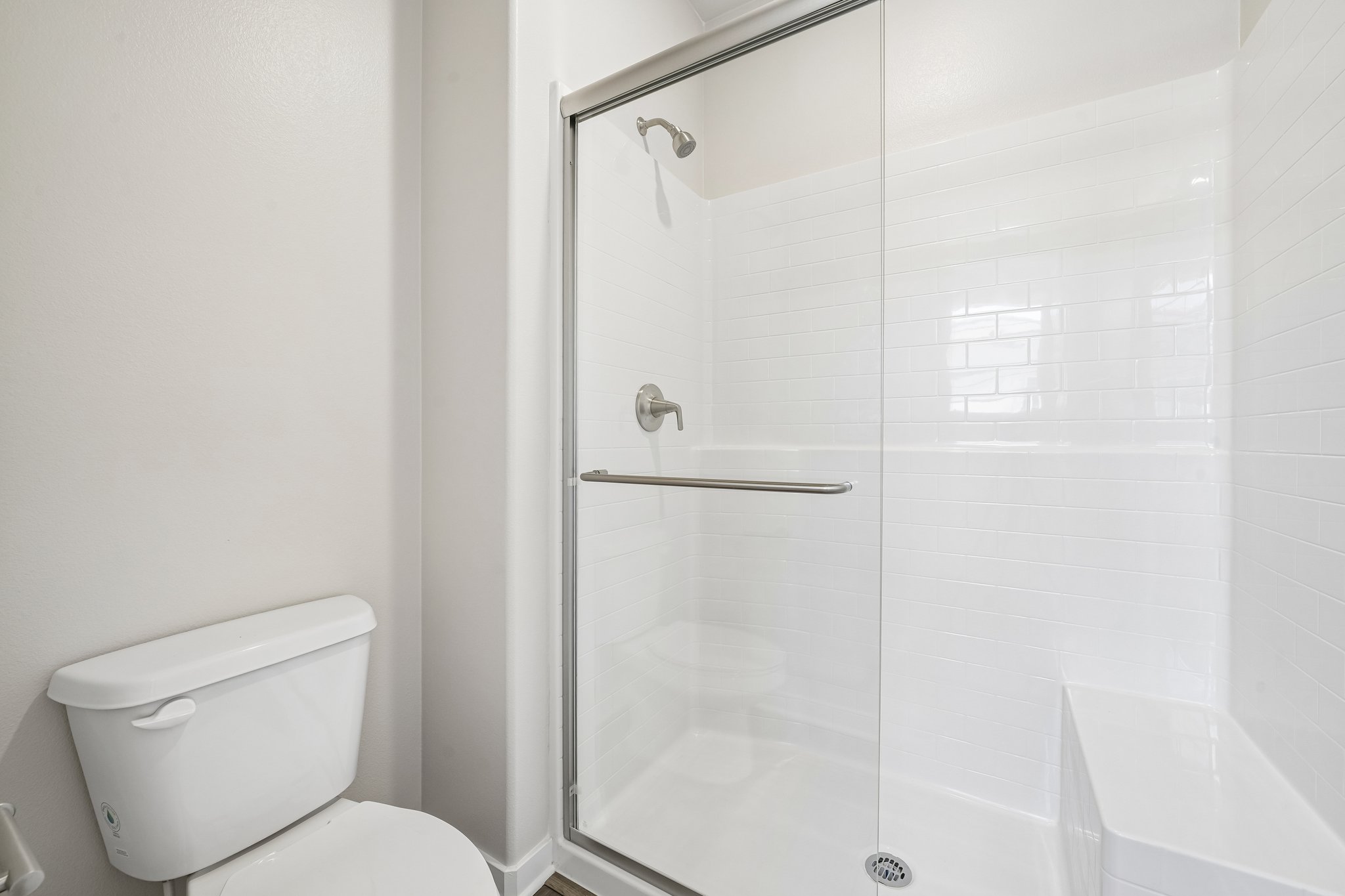 A bathroom with a shower unit and toilet.