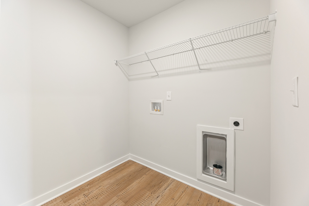 A room with a wood floor and a white wall with a white door.