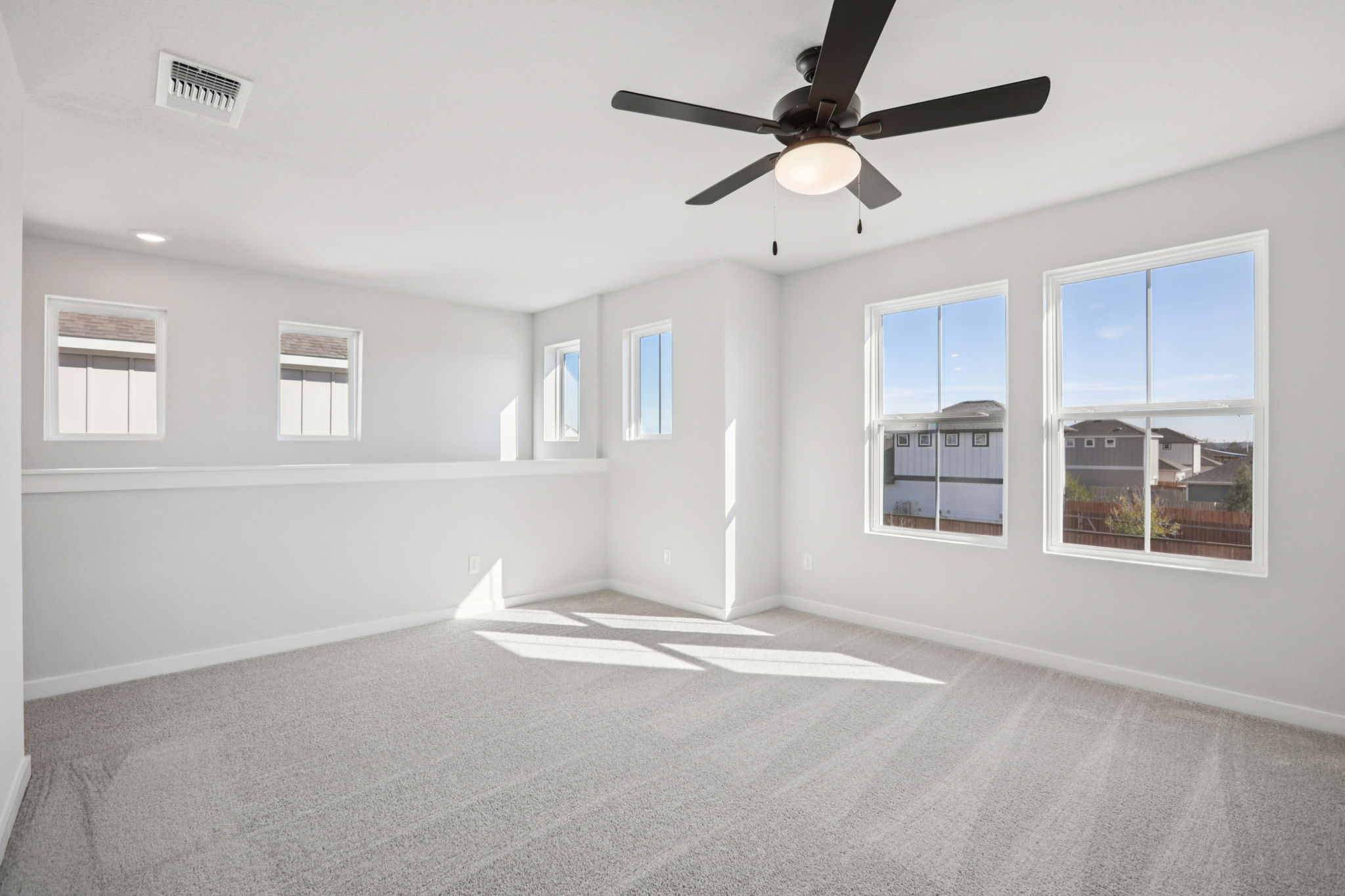 A room with a ceiling fan and windows.