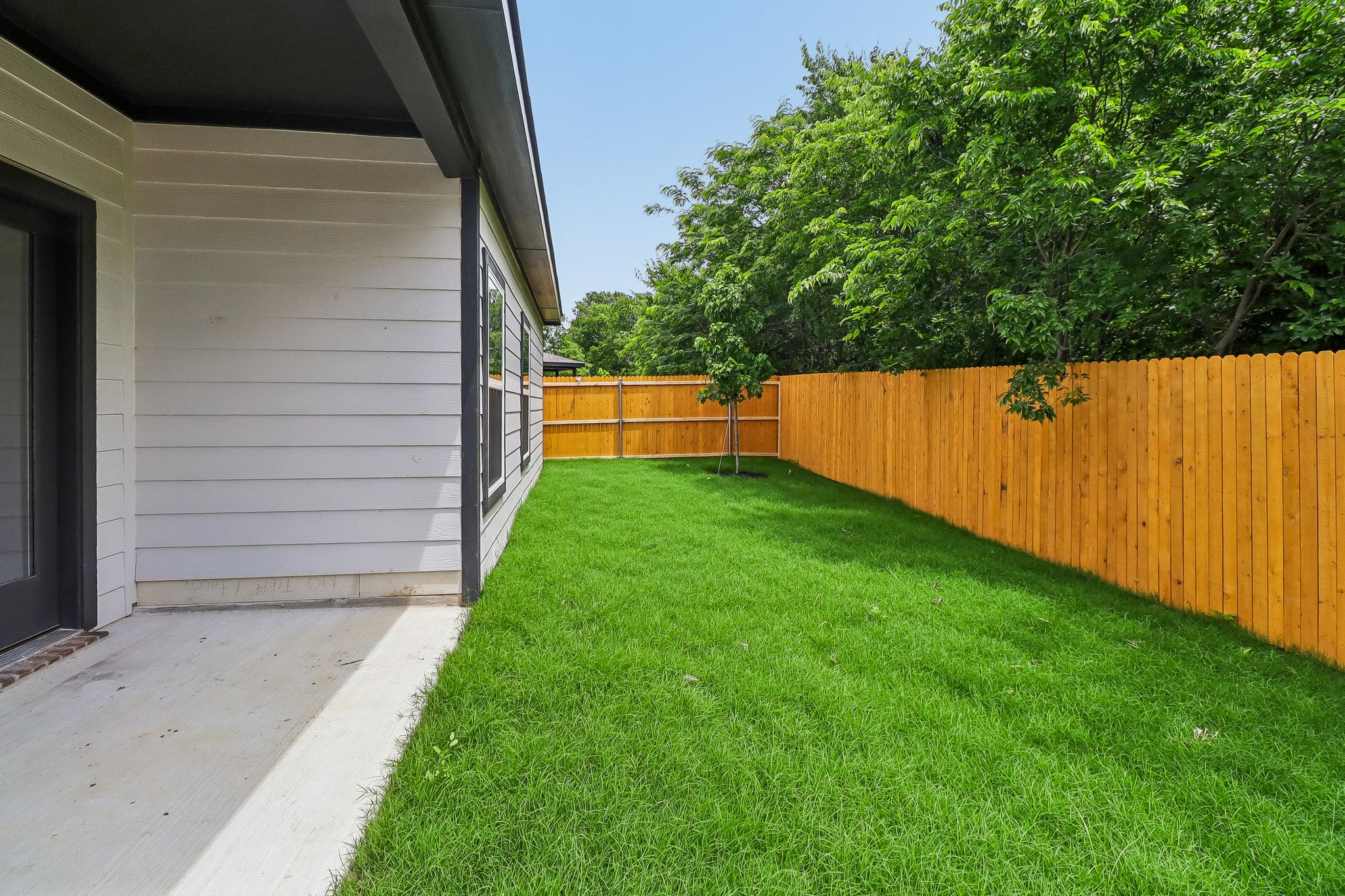 A fenced in yard with a wood fence and trees.