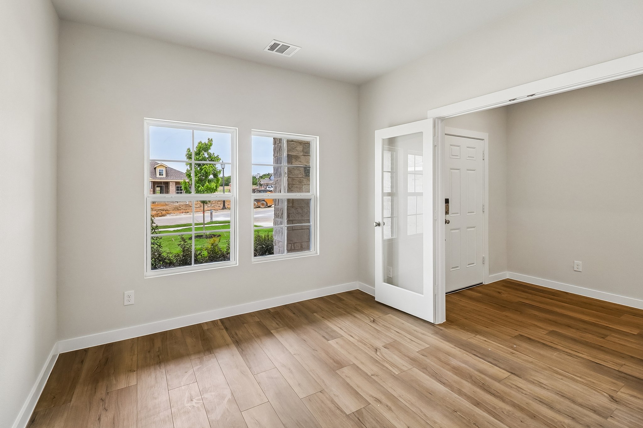 A room with a wood floor and a window with a wood floor.