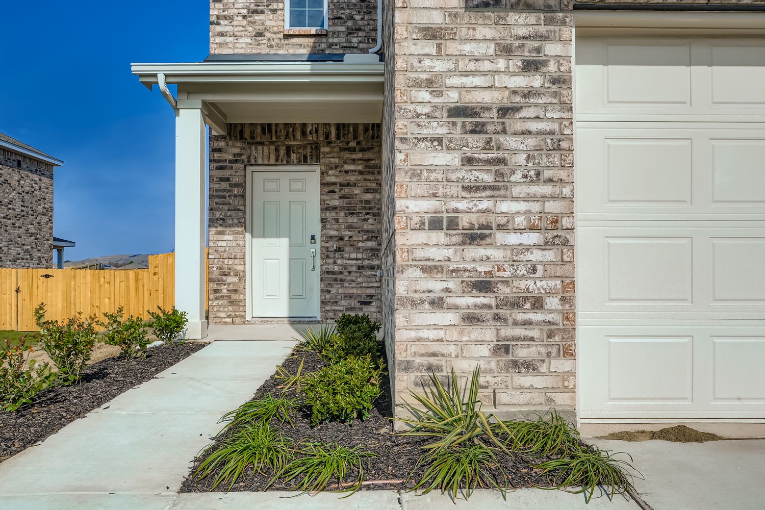 A white house with a brick driveway.