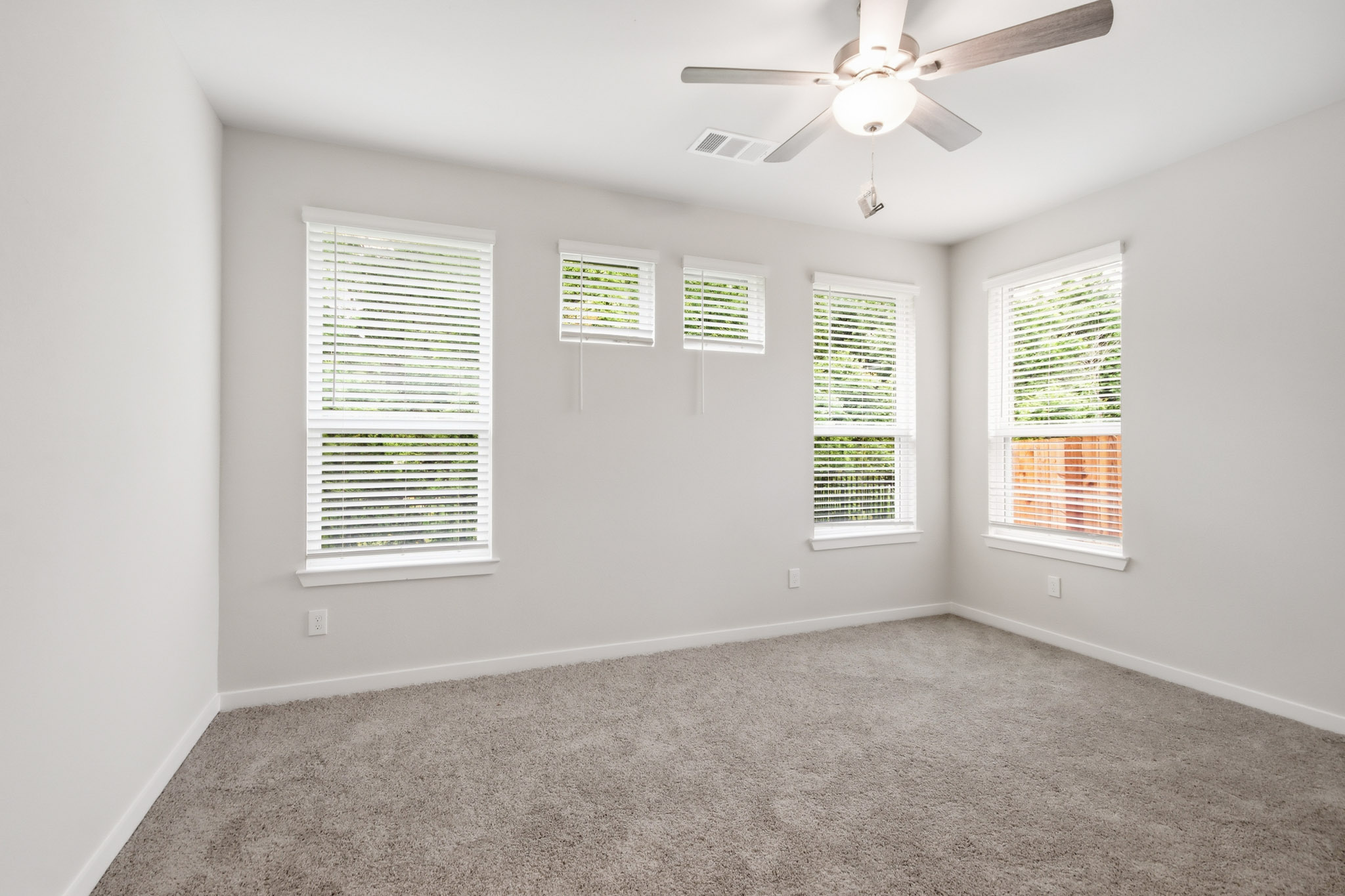 A room with a ceiling fan and windows.