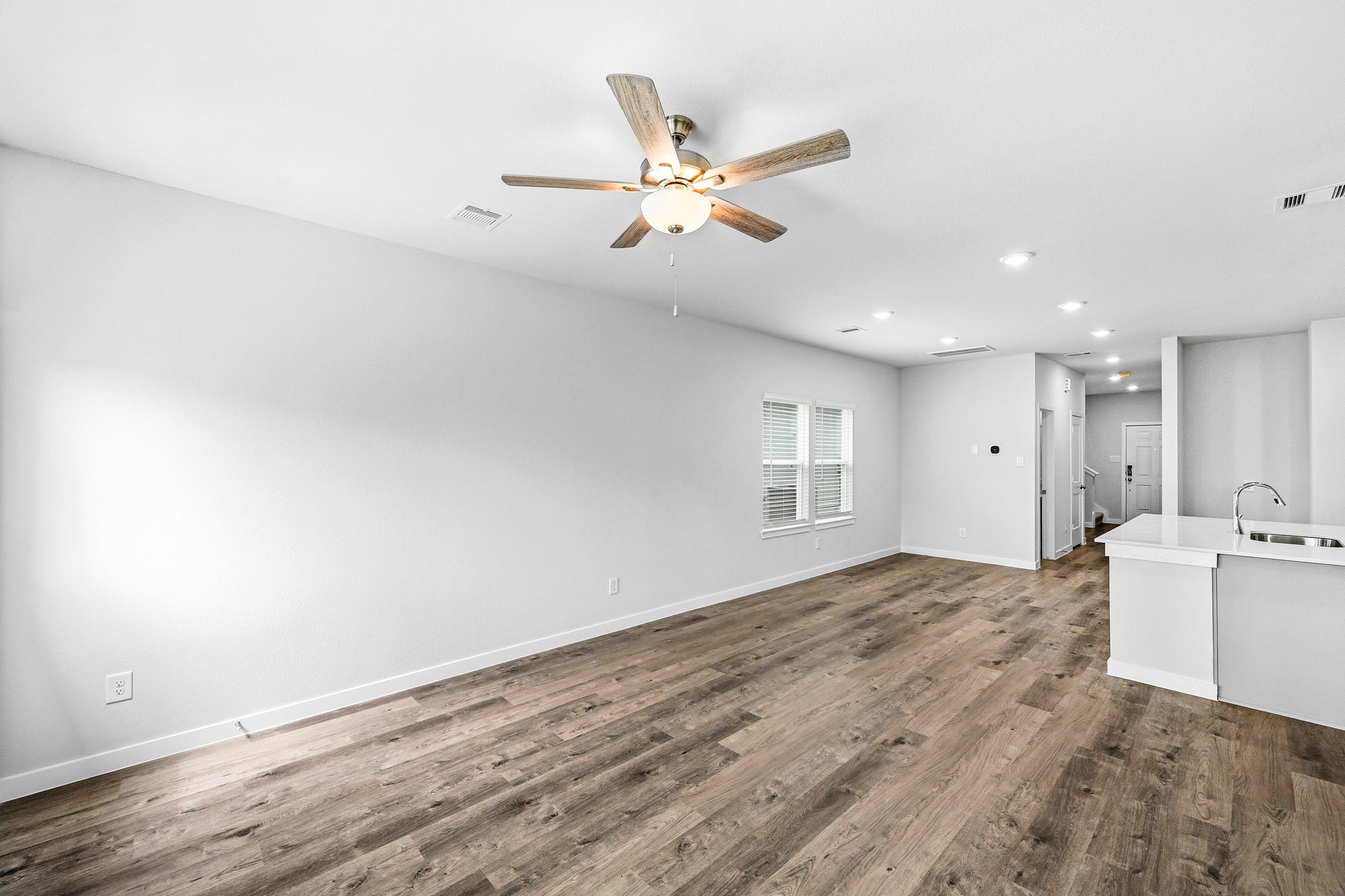 A room with a ceiling fan and a wood floor.