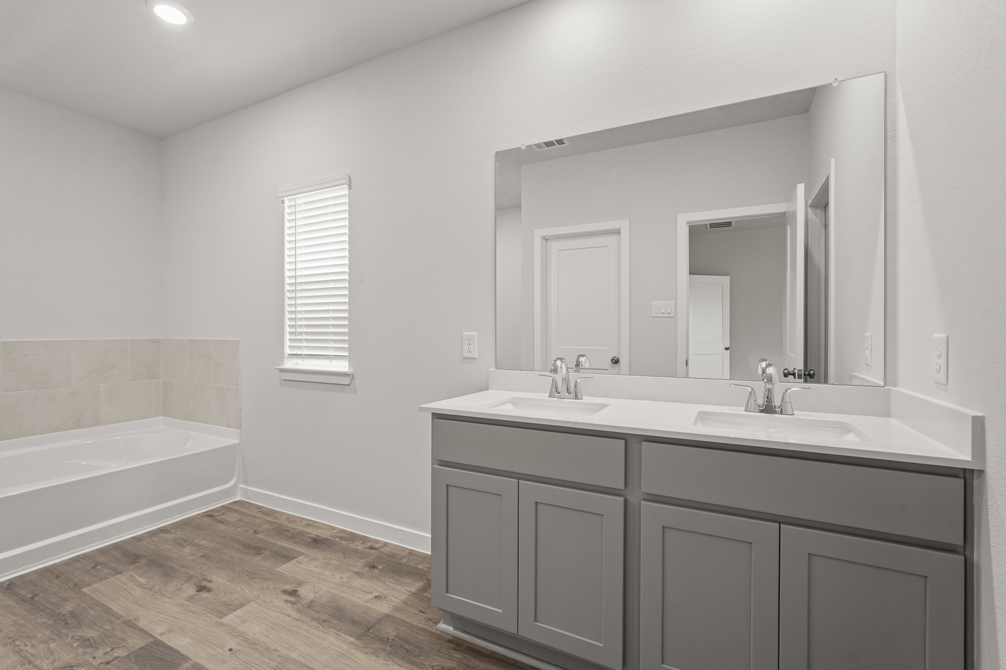 A bathroom with a tub sink and mirror.