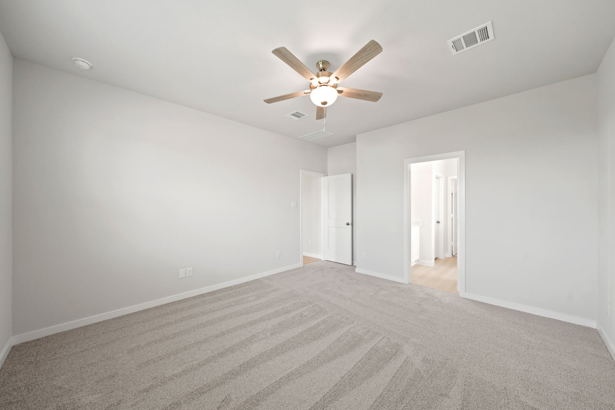 A room with a ceiling fan and a carpet.
