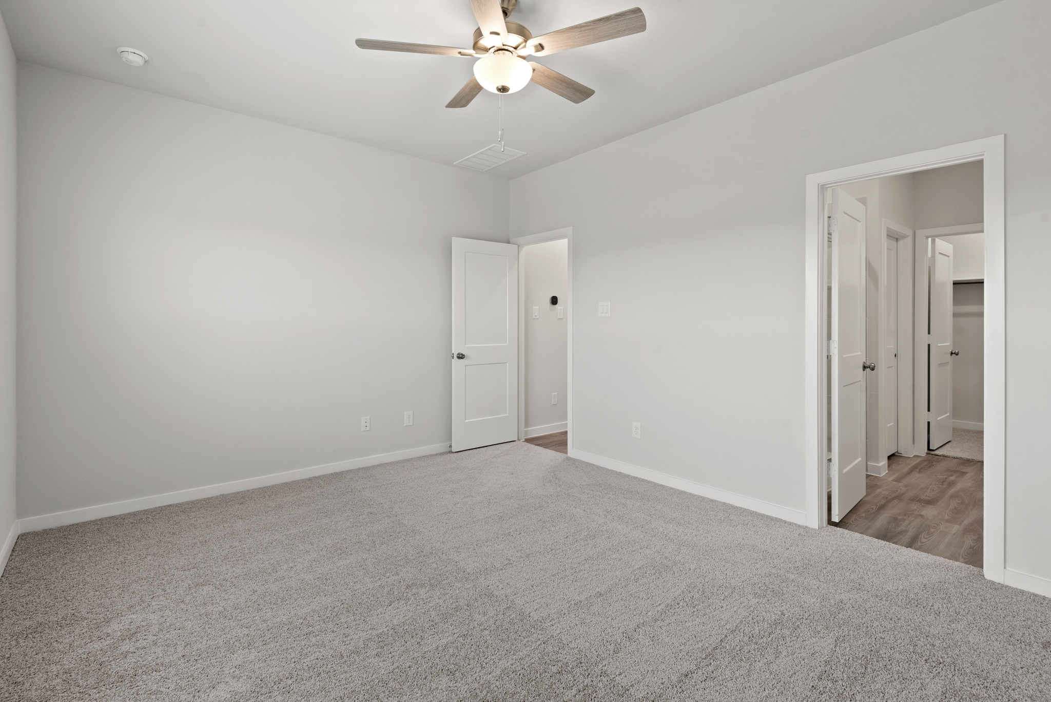 A room with a ceiling fan and white doors.