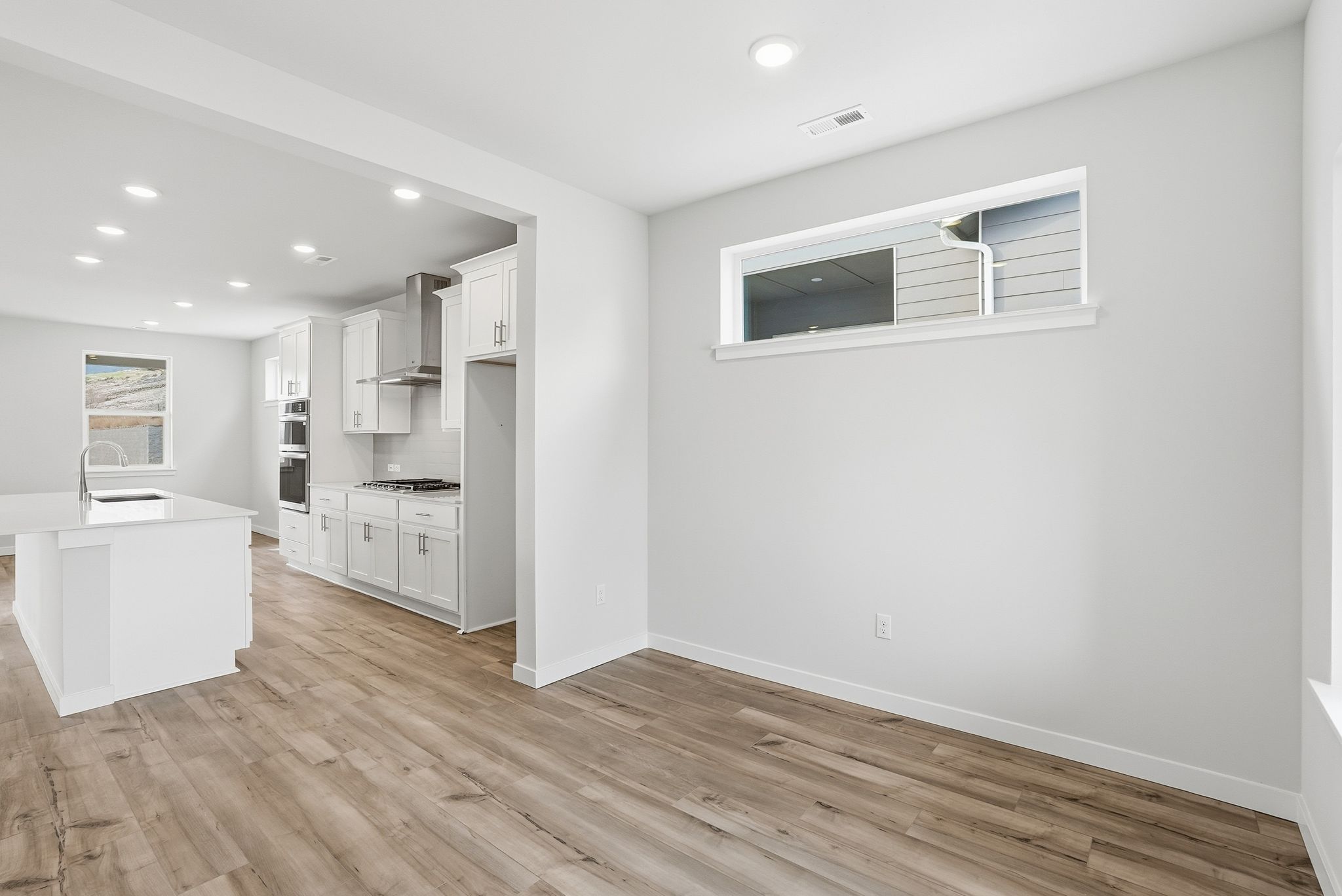A large white room with a wood floor and white cabinets.