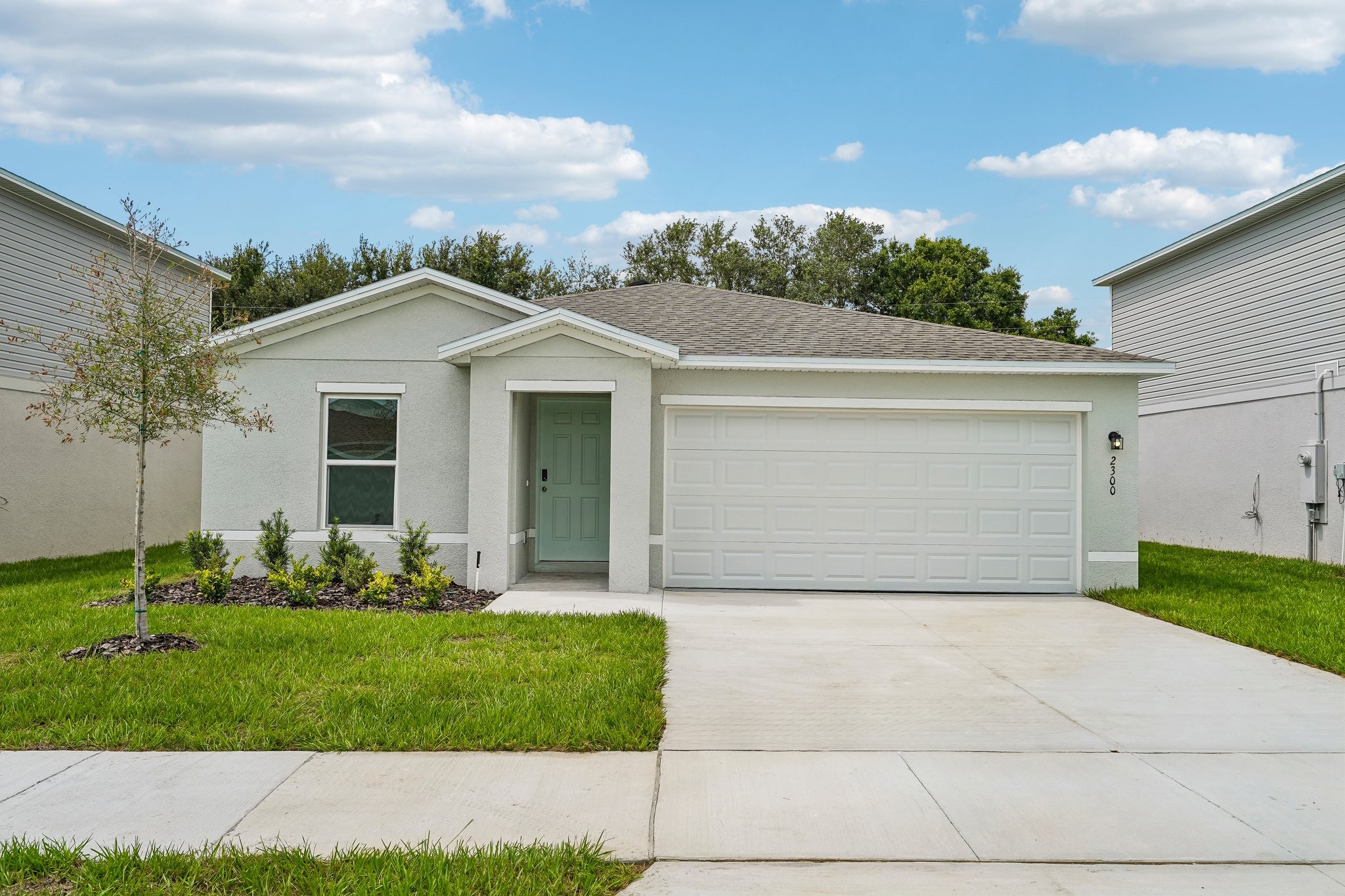 A white garage with a green lawn.